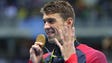 Michael Phelps holds up four fingers, for his fourth
