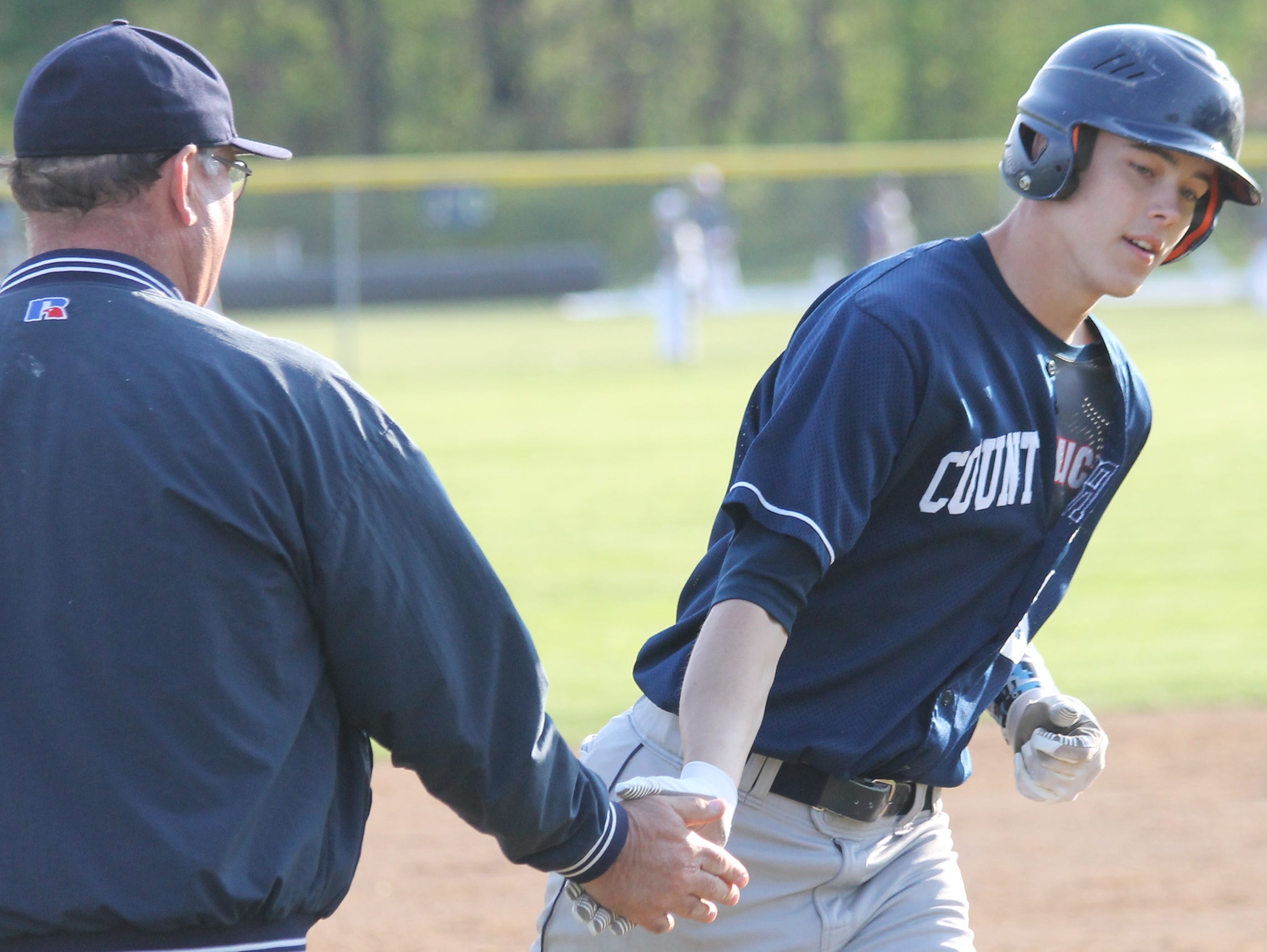 Senior Austin Richey low-fives coach Tim Dunn while rounding the bases after his grand slam against Summit April 30.