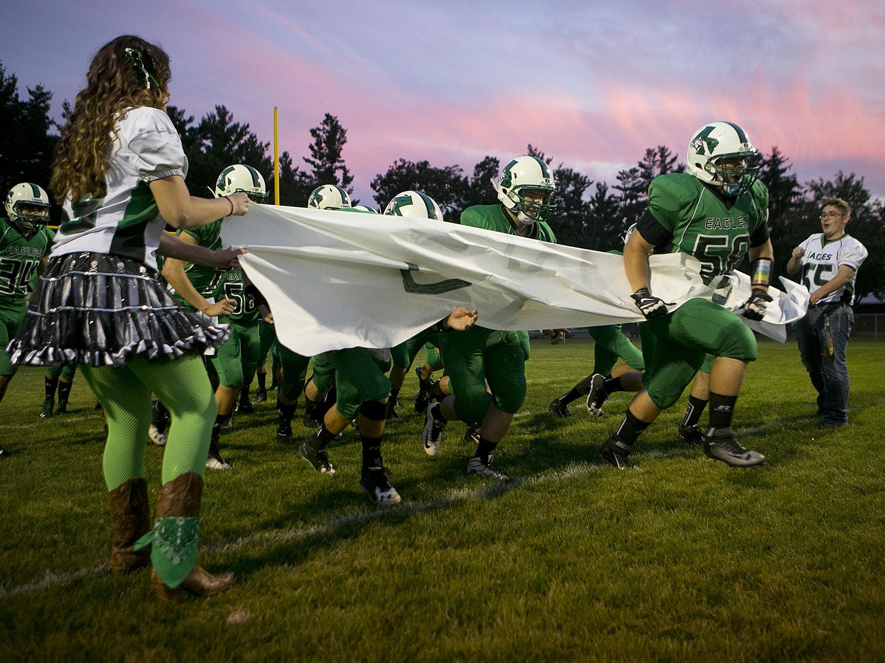Almond-Bancroft's Cole Warzynski (58) leads the team onto the field for the Central Wisconsin Conference football game against Wild Rose in Almond, Friday, Sept. 25, 2015.