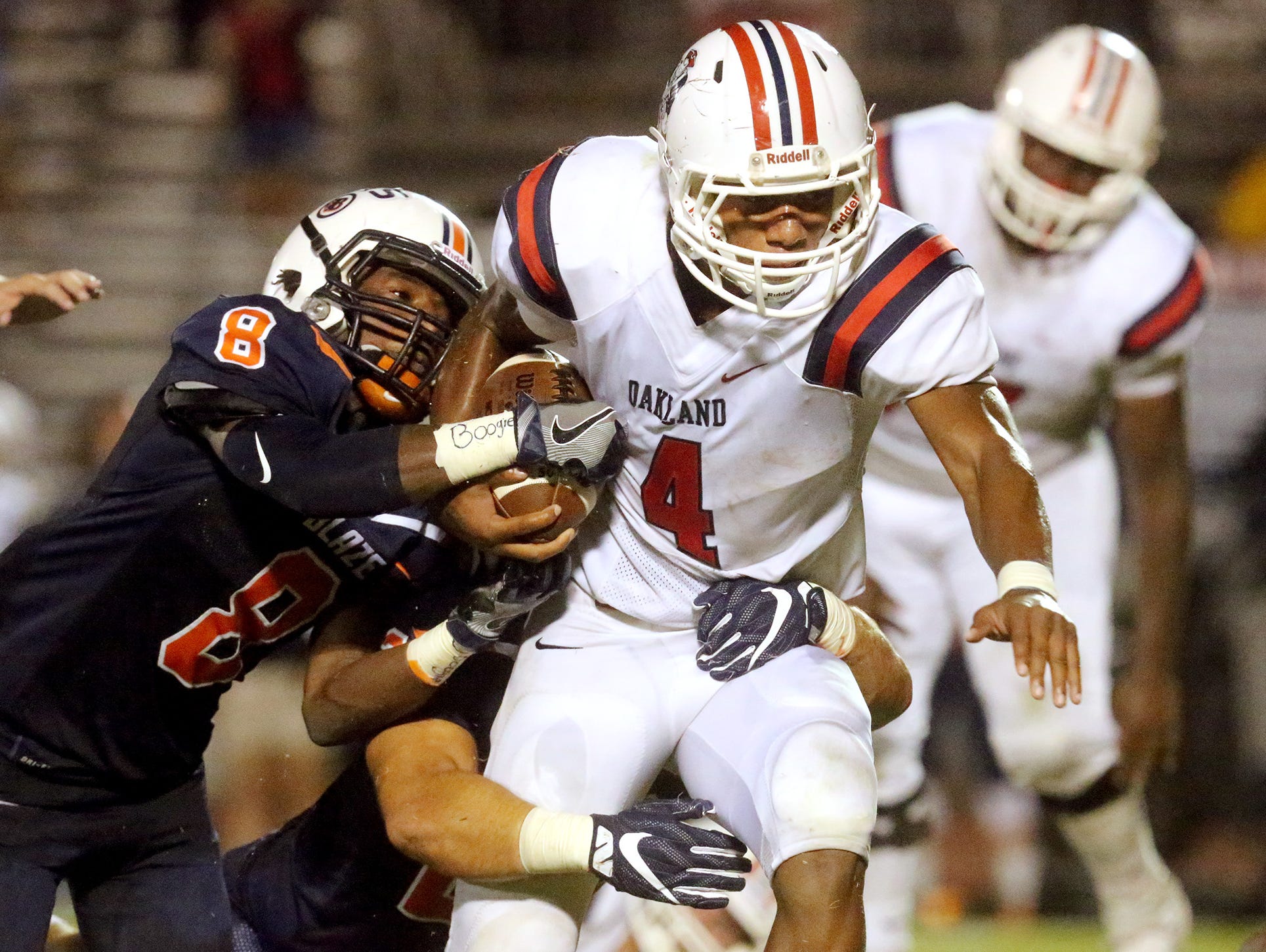 Oakland's Lazarius Patterson (4) runs the ball as Blackman's Jamis Carson (8) and Anthony Ochoa (22) tackle Patterson during the game on Friday, Sept. 16, 2016, at Blackman.