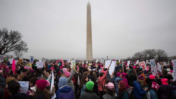 Demonstrators march past the Washington Monument during