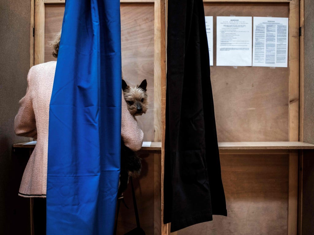 A woman with her dog votes at a polling station in Lyon, France, on April 23, 2017, during the first round of the presidential elections.