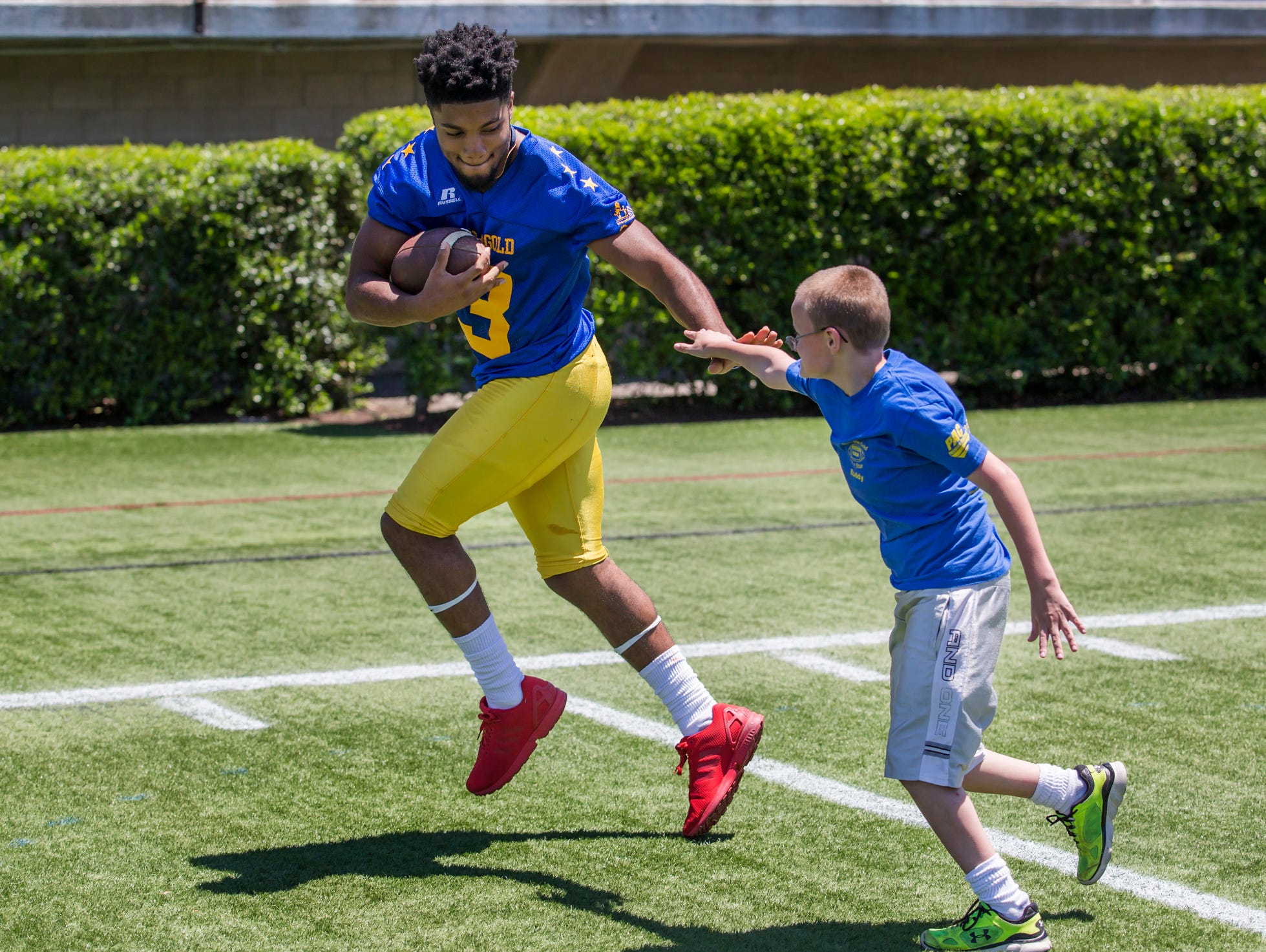 Trevon Bordrick (left) is chased down by 10 year-old Ryan Hallett during the Blue-Gold Football media day at Delaware Stadium in Newark on Sunday afternoon.
