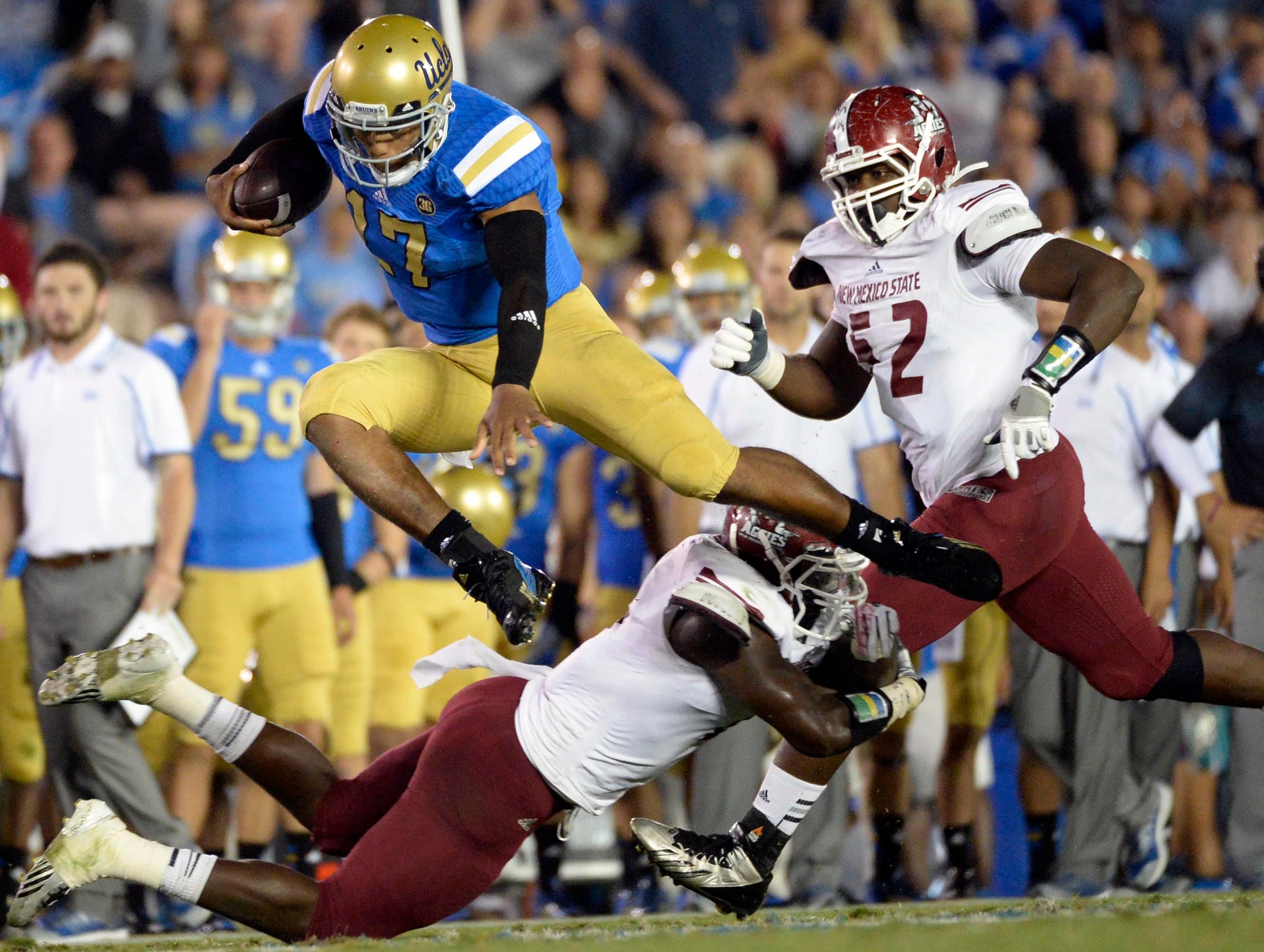 UCLA Bruins quarterback Brett Hundley leaps over a New Mexico State Aggies defender during the game at the Rose Bowl.