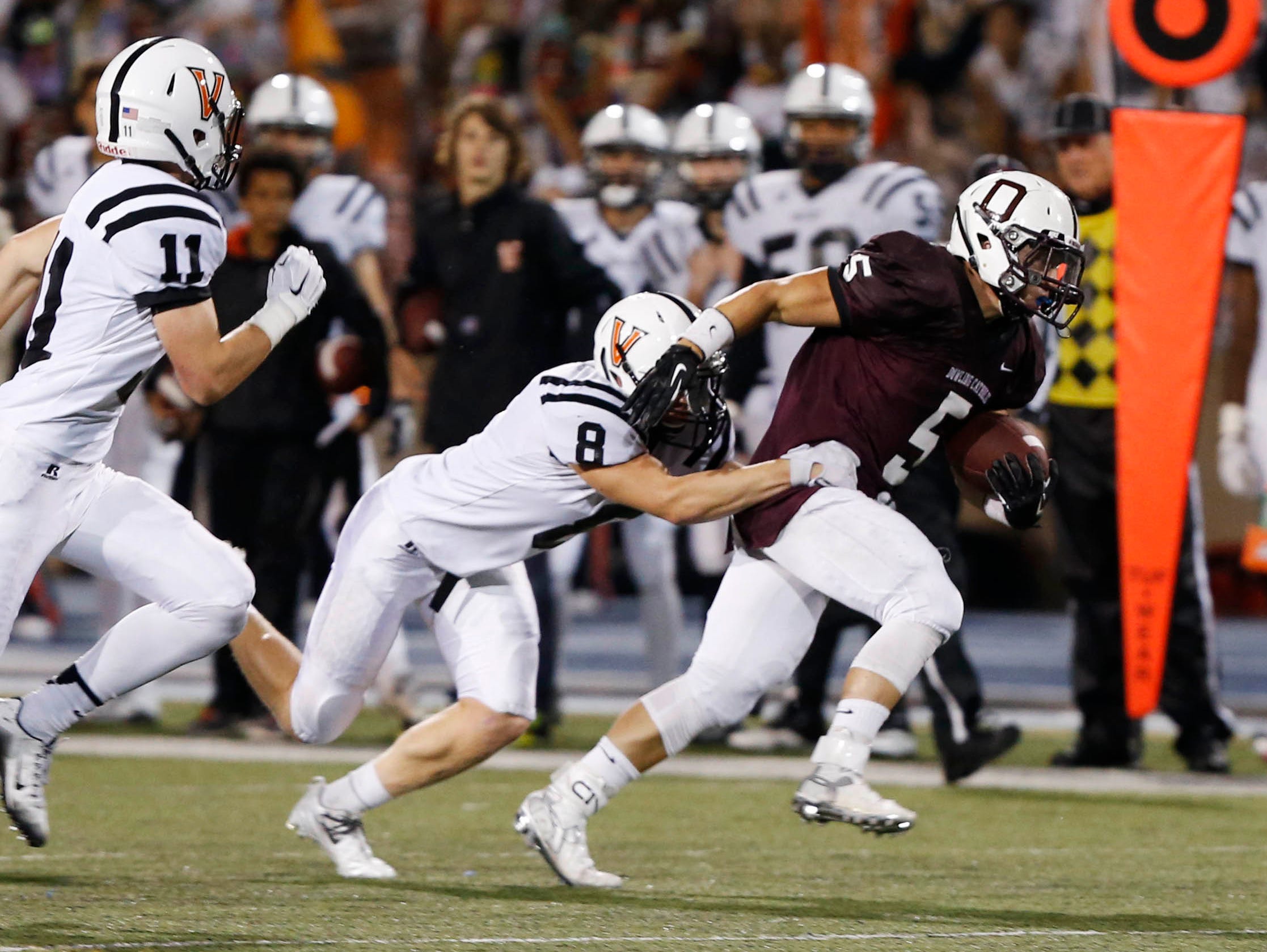 Dowling Catholic's Cole Deskin (5) tries to break away from Valley's William Phillips (8) Friday, Sept. 18, 2015, at Drake Stadium in Des Moines.