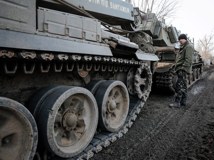A Ukrainian serviceman stands next to tanks during