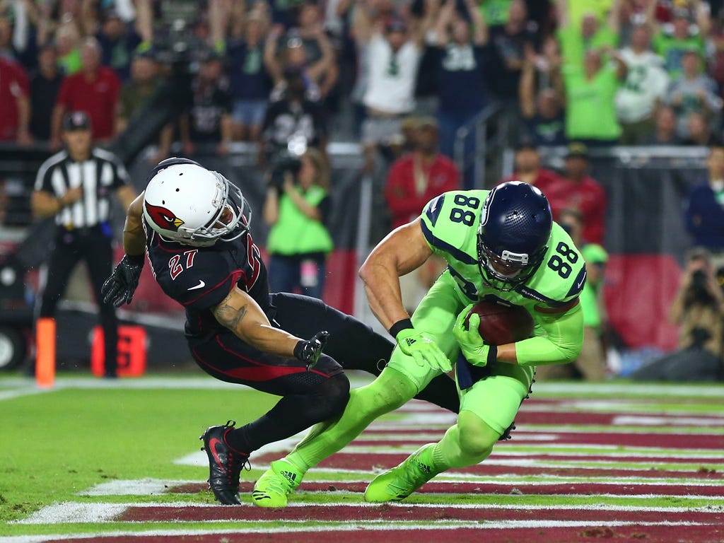 Seattle Seahawks tight end Jimmy Graham catches a touchdown pass as Arizona Cardinals safety Tyvon Branch suffers a leg injury in the first quarter at University of Phoenix Stadium.