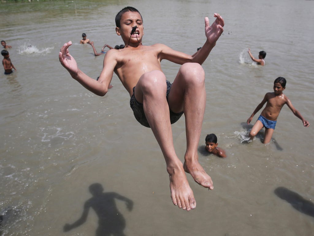 Children jump into water on a hot summer day in the Yamuna riverbed in New Delhi.