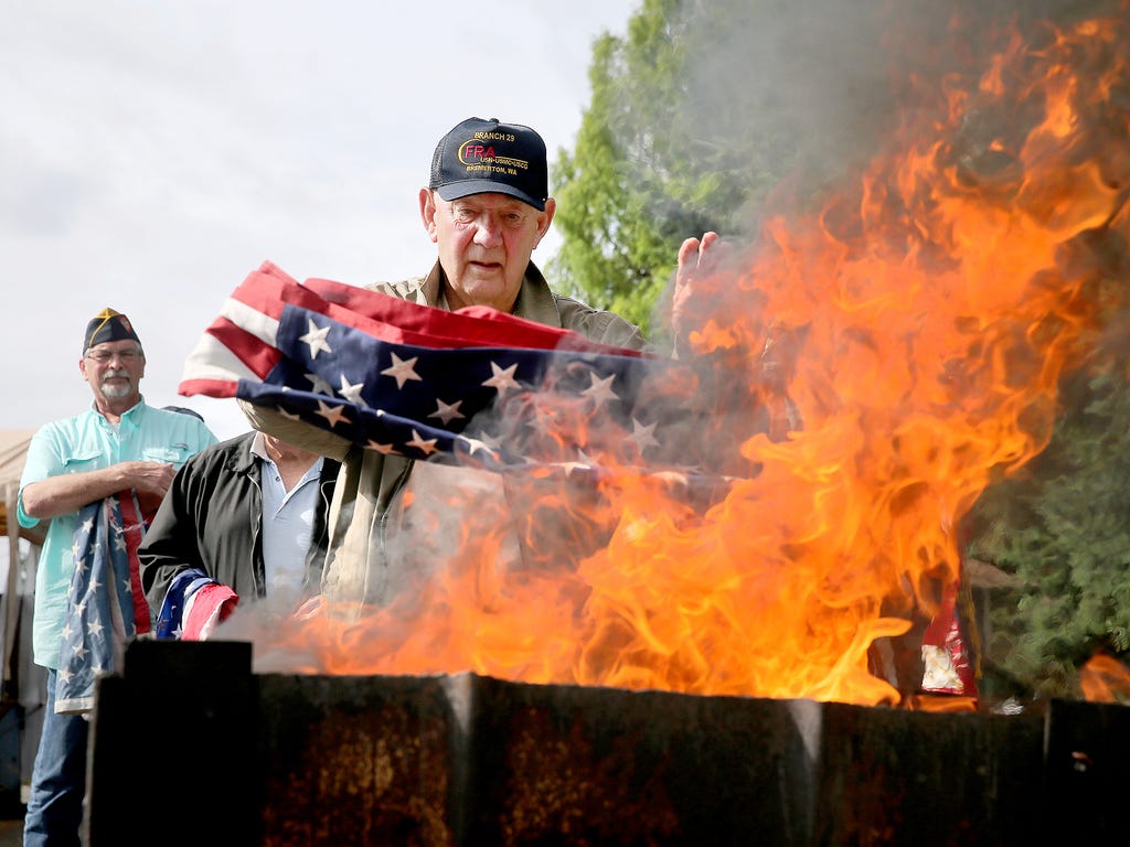 Bremerton Fleet Reserve Association Branch 29 member Glenn Wahlbrink puts a used flag in the fire pit during a flag retirement ceremony on Flag Day in Bremerton, Wash. Wahlbrink is a Korean conflict Navy veteran.