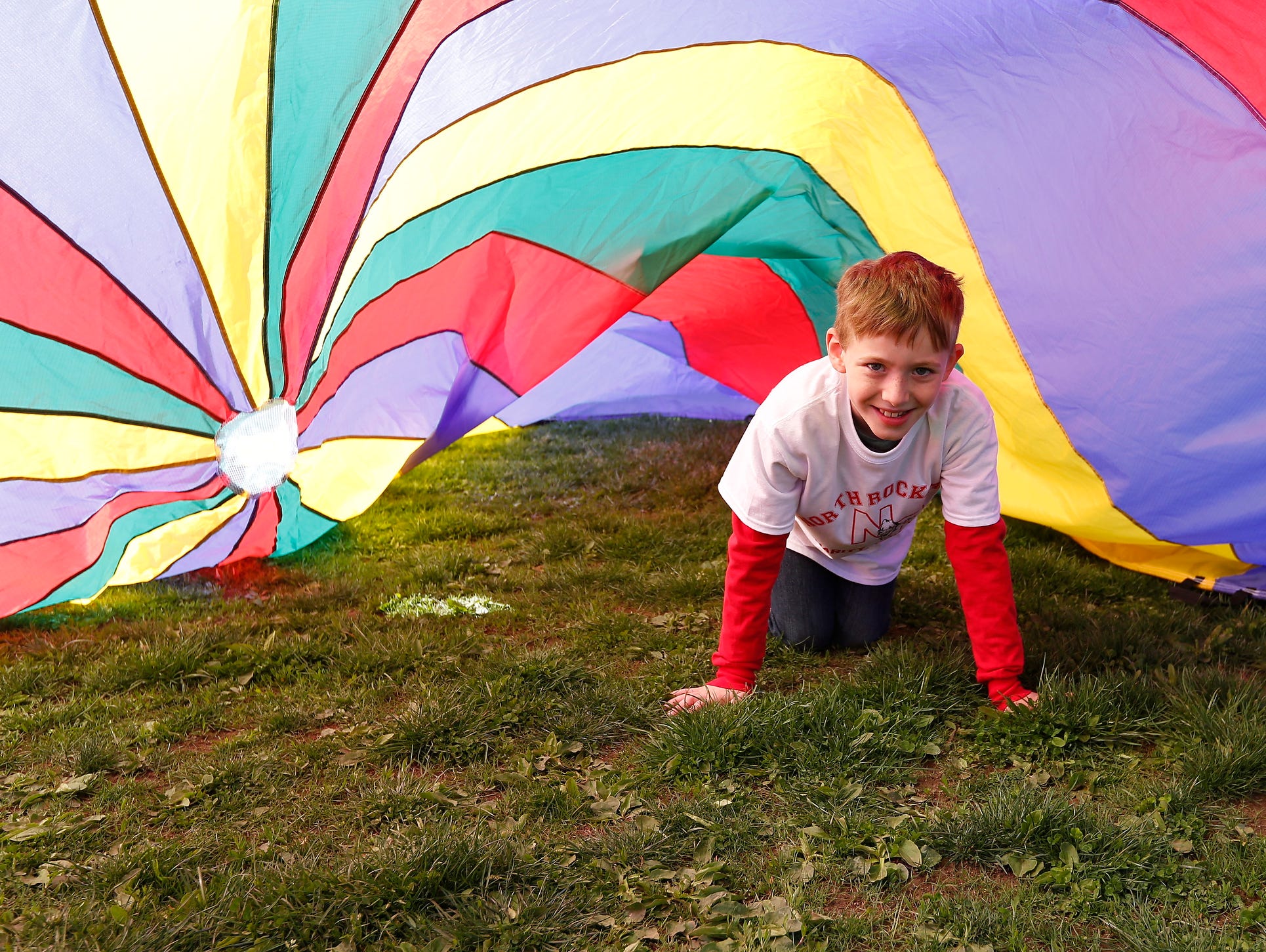 Liam McCaffrey, 8, from Stony Point crawls under a rainbow parachute at the second annual "Sports Day for Charity" event at North Rockland High School in Thiells on Saturday, April 30, 2016.