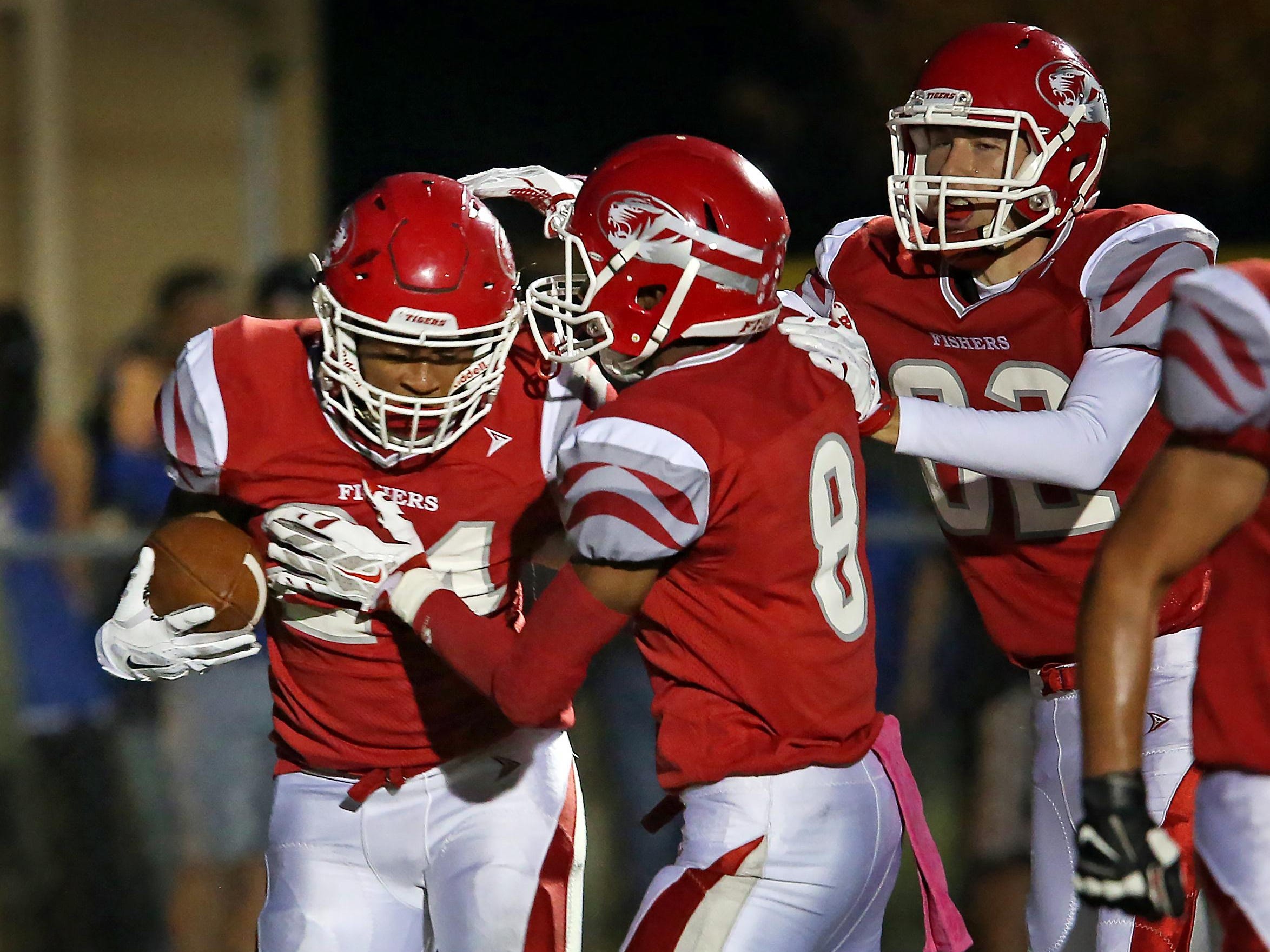 Jermaine Huddleston (left) is congratulated by teammates after he scored Fishers’ first TD in the Tigers’ win over Hamilton Southeastern.