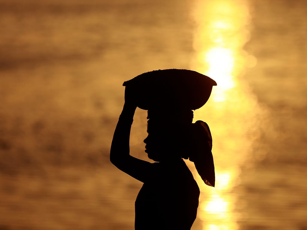 An Indian woman laborer carrying sand at a construction site is silhoutted against the Arabian Sea on International Women's Day in Mumbai, India on March 8, 2017.