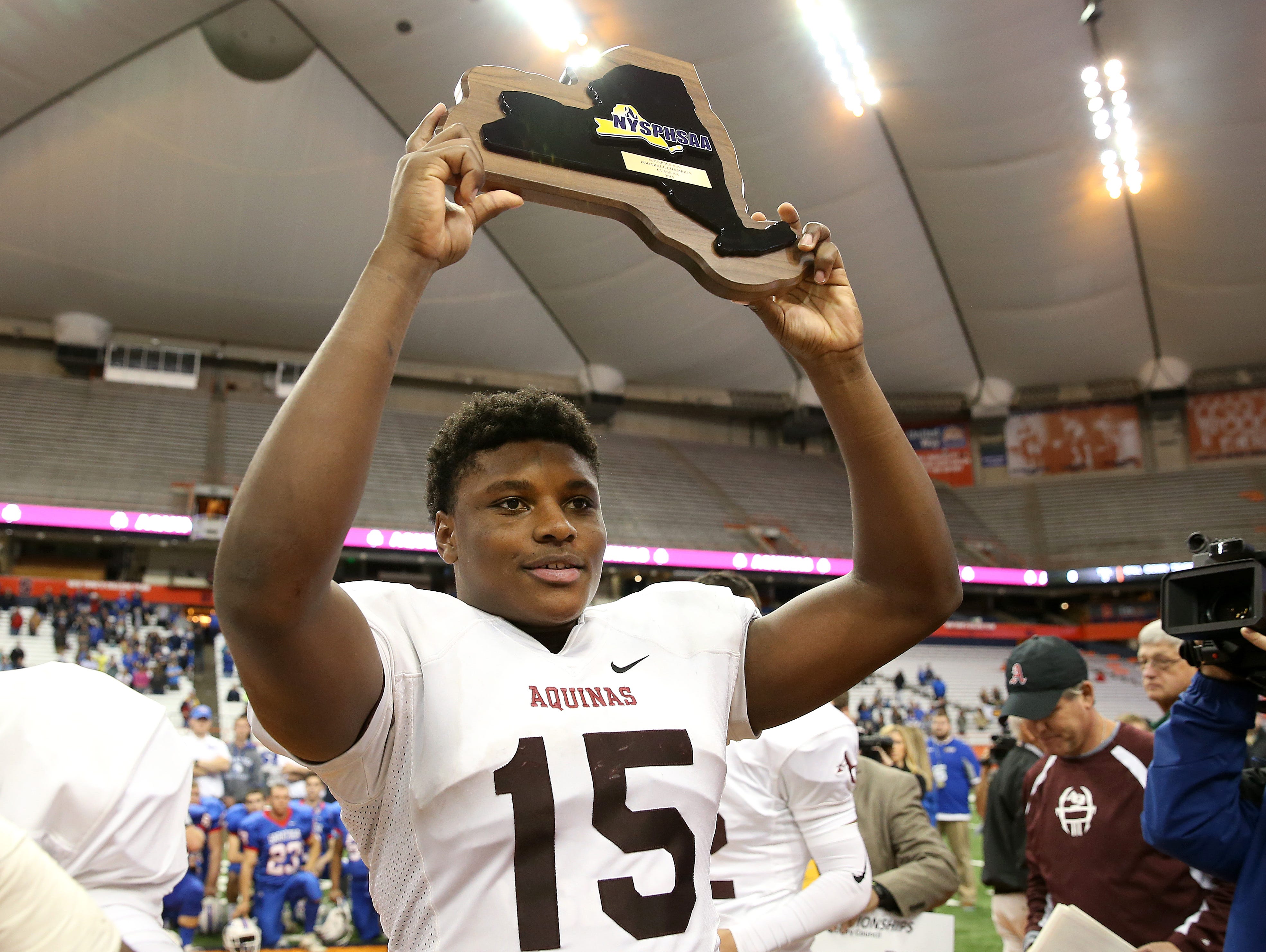 Jamir Jones holds up the championship plaque after beating Saratoga Springs 44-19 to win State Class AA title.