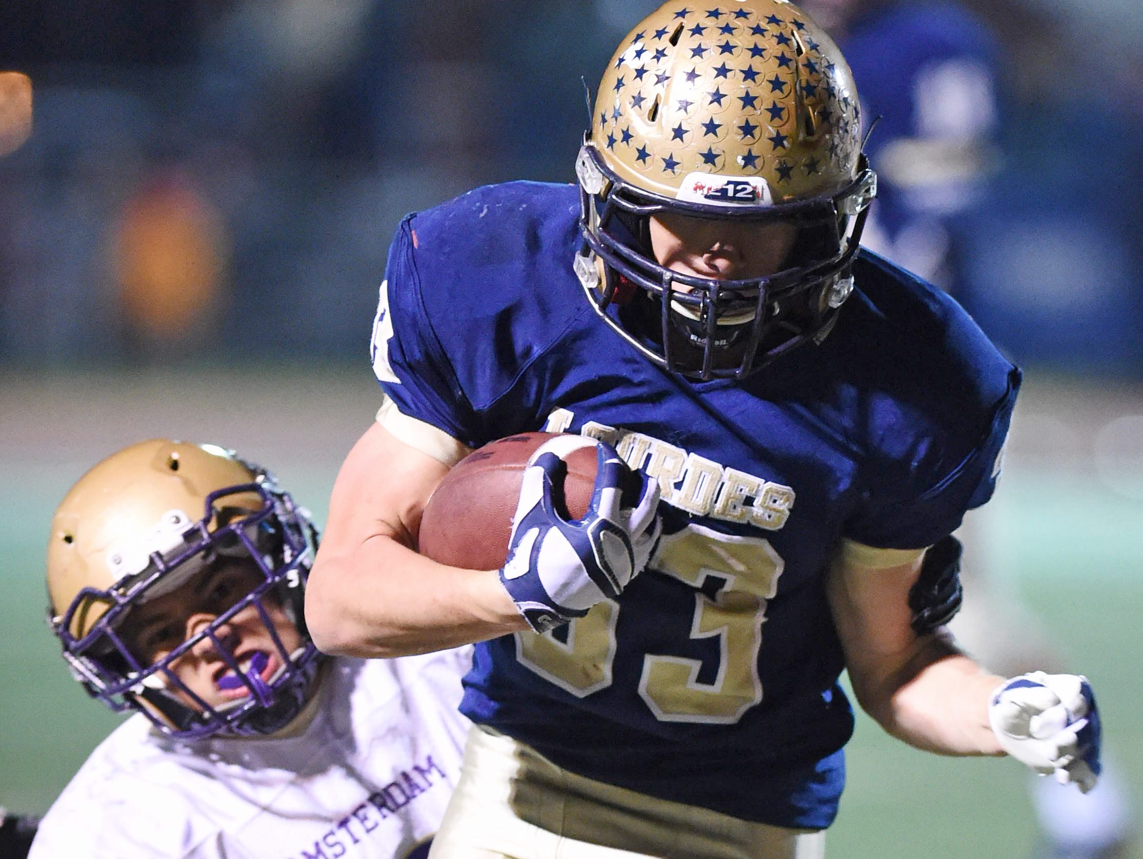 Lourdes' Joe Scaglione carries the ball as Amsterdam's Adel Rosario grabs a hold of him during the Class A semi final at Dietz Stadium.