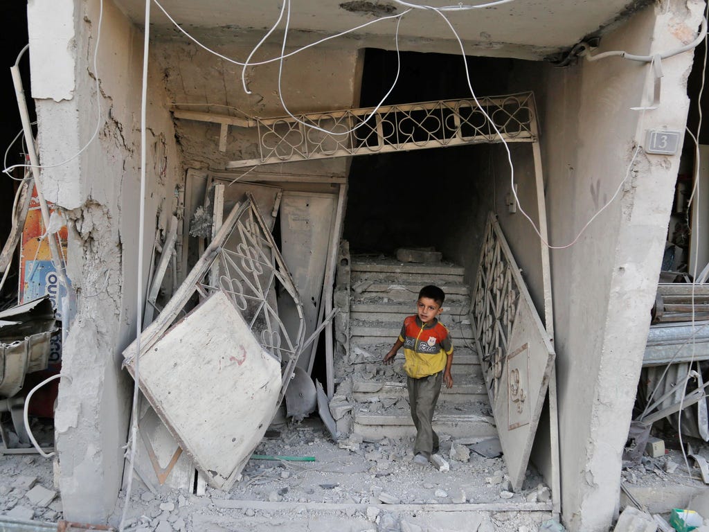 A Syrian child walks out of a damaged building on July 25, 2017, following an air strike late the previous night on the rebel-held town of Arbin, east of the capital. \u000dWomen and children were among the dead in the 11:30 pm  strike on Arbin in th