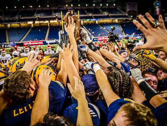Members of the Ithaca football team lift the Division 6 state championship trophy after their come from behind win over Clinton Friday November 27, 2015 at Ford Field in Detroit.