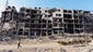 A Palestinian shepherd leads his flock of sheep past an apartment complex in Gaza City, that was heavily damaged in fighting between Israel and Hamas.