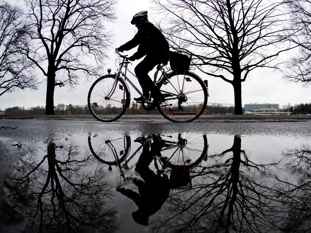 A woman on a bicycle is reflected in a puddle in Hanover, northern Germany, on Dec. 30, 2017.