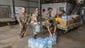 Troops put food and water supplies onto a pallet for