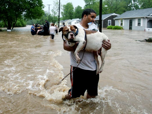 Andrew Hudson carries his dog Sugar after being rescued