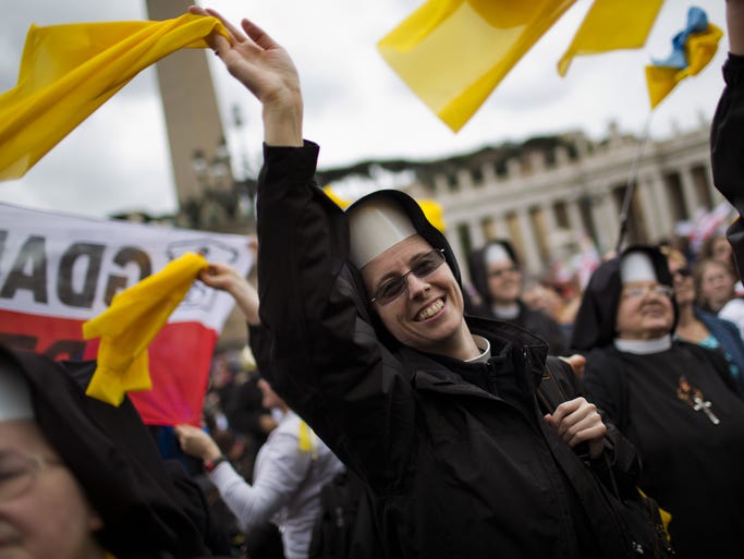 Nuns wave as Pope Francis is driven through the crowd after presiding over a solemn ceremony in St. Peter's Square at the Vatican, Sunday, April 27, 2014. Pope Francis has declared his two predecessors John XXIII and John Paul II saints in an unprecedented canonization ceremony made even more historic by the presence of retired Pope Benedict XVI.