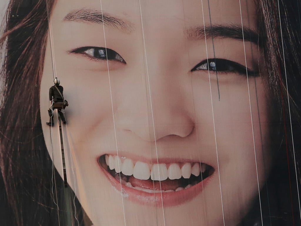 A worker hangs on a rope to adjust an image on a building in Seoul, South Korea.