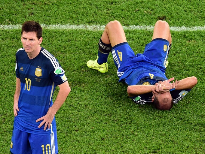 Argentina's Pablo Zabaleta lies on the pitch as Lionel Messi stands beside him after losing to Germany in the final.