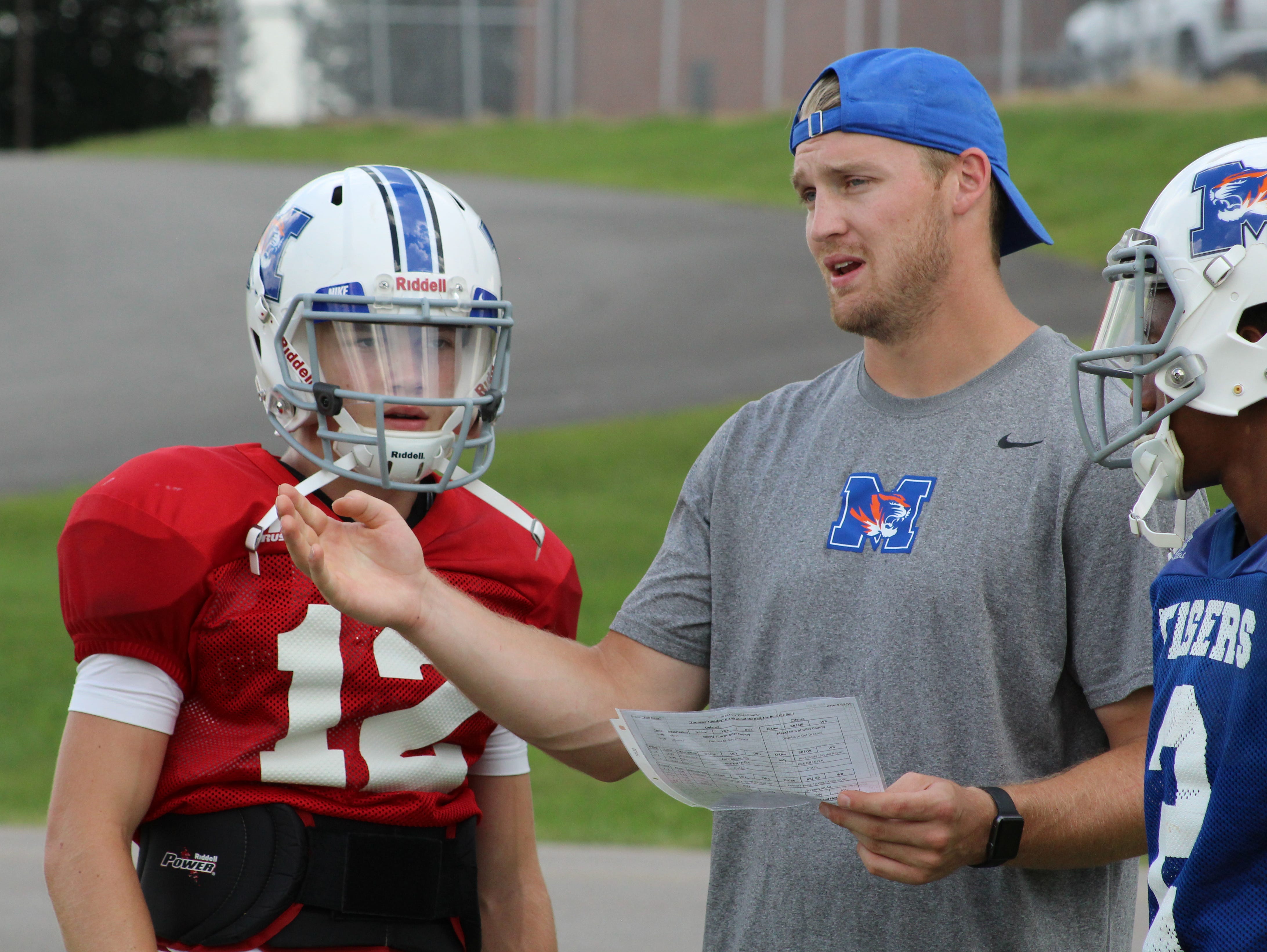 Marshall County quarterbacks coach Bo Wallace gives his brother Bryce Wallace instruction during a drill.