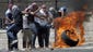 Palestinian protesters roll a burning tire at Israeli police in Shuafat.
