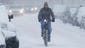 Bundled against high winds, a bicyclist struggles down