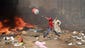 A demonstrator throws a water container onto a fire.