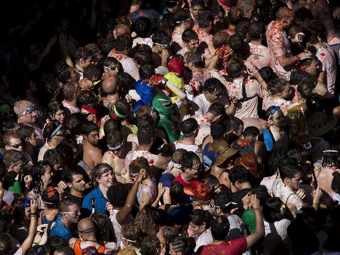 People are packed together on a street during the tomato throwing festival.