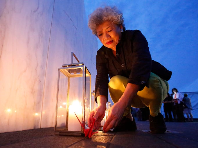 Yachiyo Kuge, the mother of Toshiya Kuge, places paper origami birds near his name at the Flight 93 National Memorial in Shanksville, Pa. The memorial marks the spot where United Airlines Flight 93 crashed 13 years ago after passengers fought back against hijackers.
