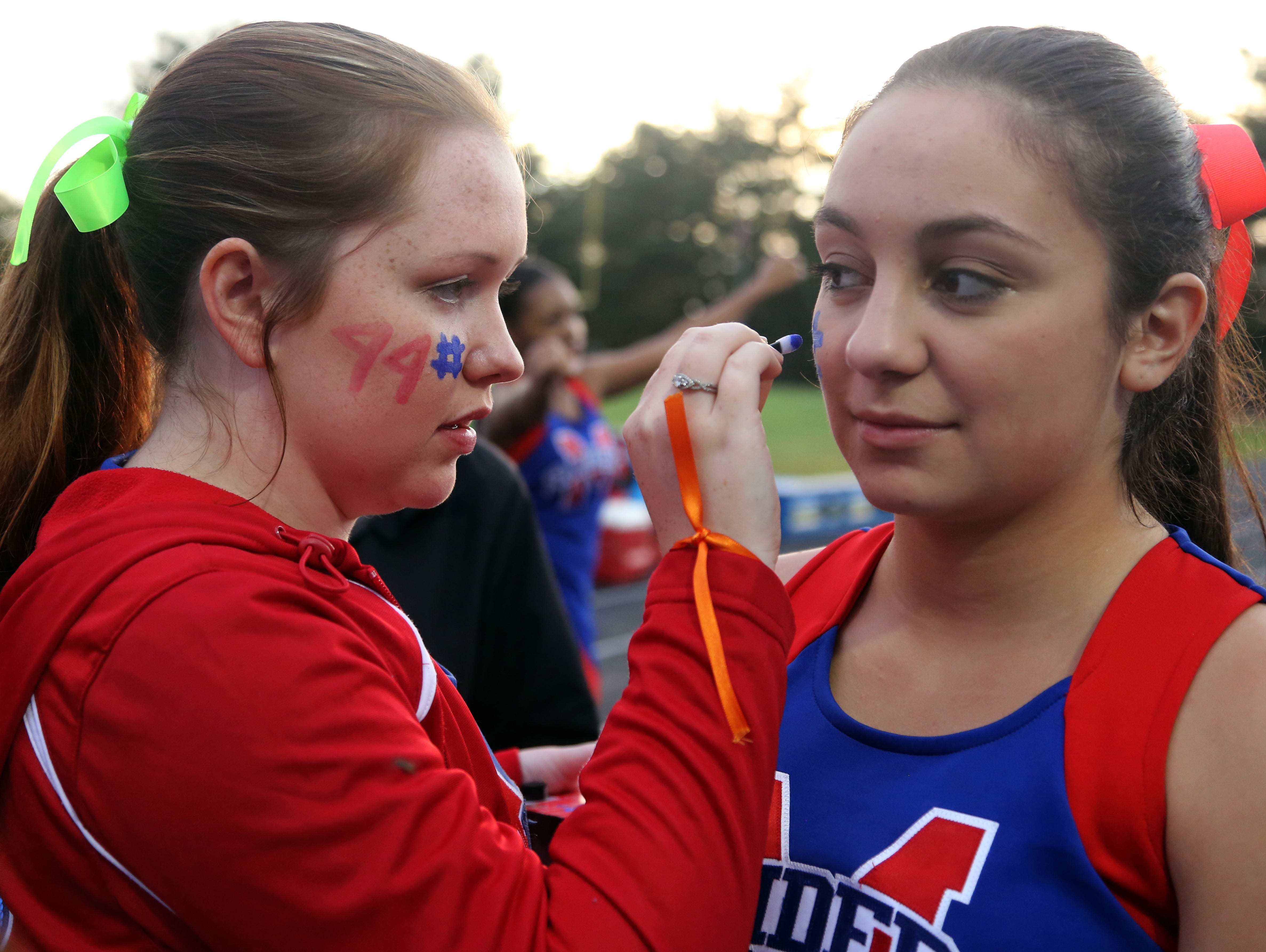 McGavock cheerleader Alaina Solis, left, paints #44 on fellow cheerleader Lauren Estrada's cheek in honor of football player Hunter Jackson, who wore No. 44, prior to the start of their home game against Cane Ridge in September.