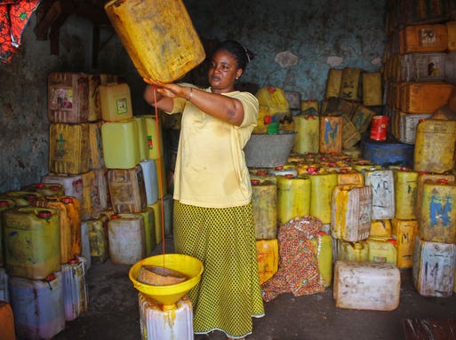 Palm oil vendor Pauline Haba pours palm oil from a container on Aug. 26. Her business is suffering because no one wants to buy her palm oil, which comes from an area where the Ebola outbreak has cost many lives in Conakry, Guinea.