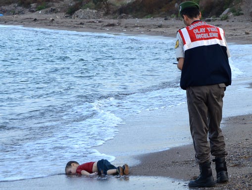 A Turkish police officer stands next to a migrant child's