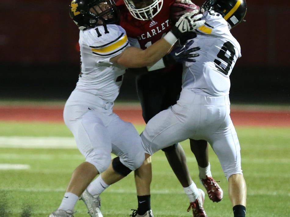 Southeast Polk’s Braeden Vasey, left, and Bradley VanHeeswyk tackle Isaac Toluwalase of Des Moines East during a 56-7 win on Friday at Williams Stadium.