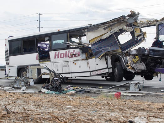 The wreckage of a tour bus is removed by workers on