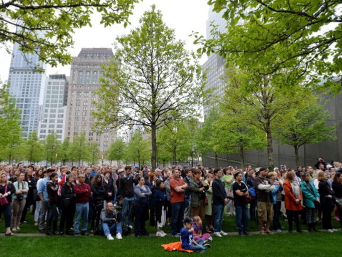 NEW YORK, NY - MAY 15: People gather on the plaza of the National September 11 Memorial to watch the telecast of the dedication ceremony for the museum at ground zero May 15, 2014 in New York City. The museum spans seven stories, mostly underground, and contains artifacts from the attack on the World Trade Center Towers on September 11, 2001 that include the 80 ft high tridents, the so-called "Ground Zero Cross," the destroyed remains of Company 21's New York Fire Department Engine as well as smaller items such as letter that fell from the hijacked plane and posters of missing loved ones projected onto the wall of the museum. The museum will open to the public on May 21. (Photo by Justin Lane-Pool/Getty Images)