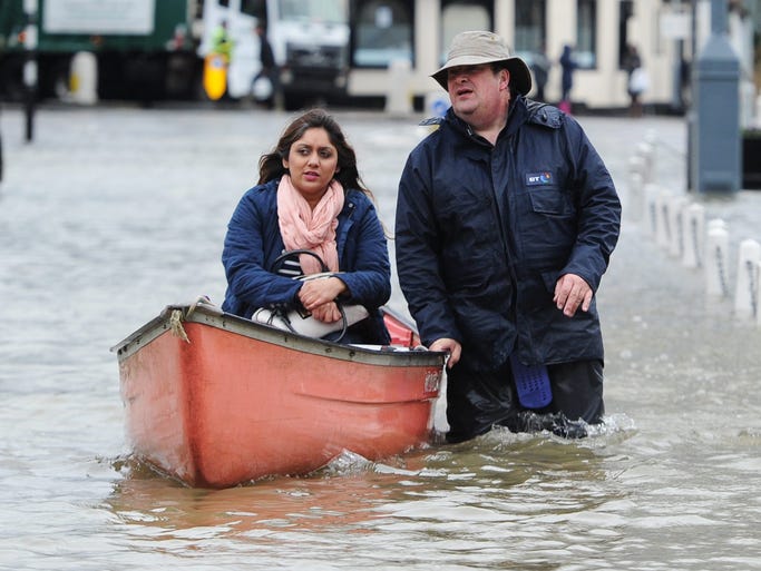 A woman is transported by canoe to dry ground in the flooded village of Datchet along the Thames river.