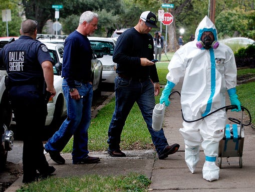A man dressed in protective clothing leaves after treating