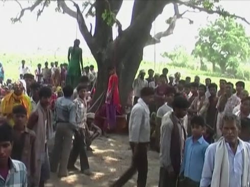 Villagers gather around the bodies of two teenage sisters hanging from a tree in Katra village, India, on May 28, 2014.