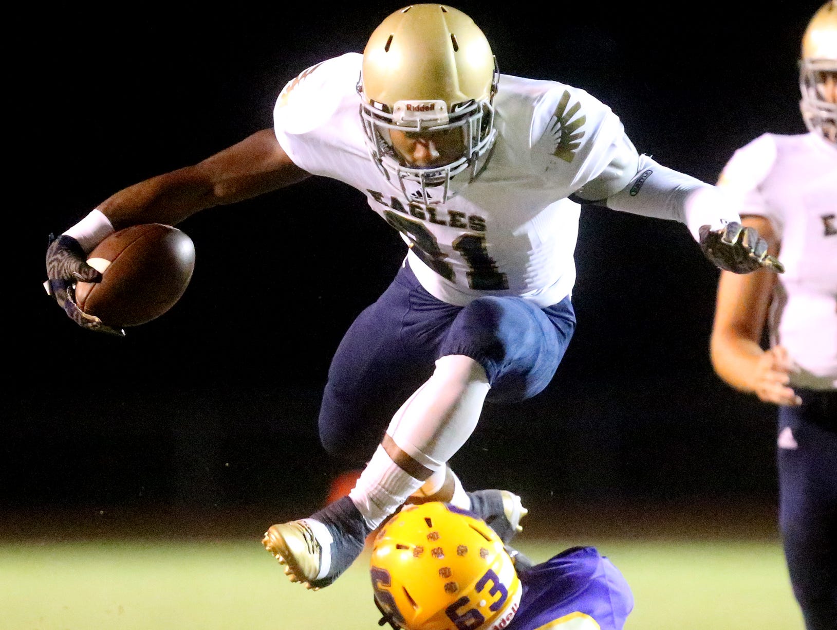 Independence's Troy Henderson (21) hurdles over players as he runs the ball during the game against Smyrna.