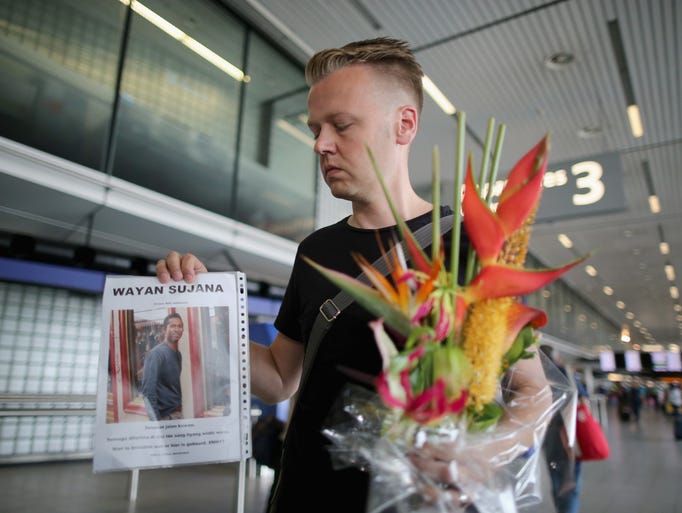 Arthur Laumann holds a floral tribute and photograph of family friend Wayan Sujana of Bali.
