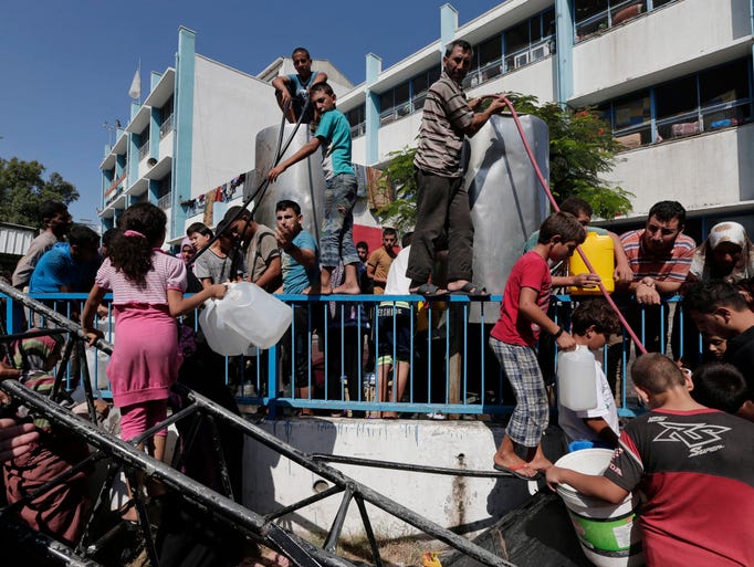Displaced Palestinians wait to collect water at a United Nations school where their families are taking refuge in Gaza City.