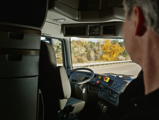 An Otto truck driver watches the wheel from the cab