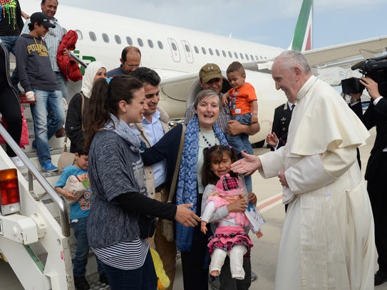 Pope Francis greets a group of Syrian refugees upon