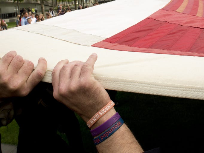 The hands of a fireman are seen as members of the public hold the National 9/11 Flag during a ceremony marking the opening of the 9/11 Memorial Museum on May 21, 2014 in New York. After the ceremony the flag was transferred into the museum's permanent collection. AFP PHOTO/Don Emmert (Photo credit should read DON EMMERT/AFP/Getty Images)