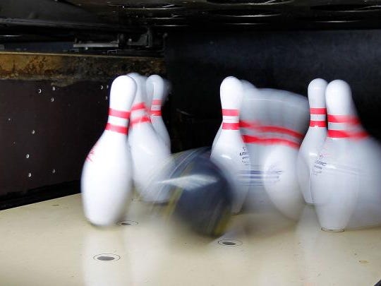 A bowling ball hits pins.