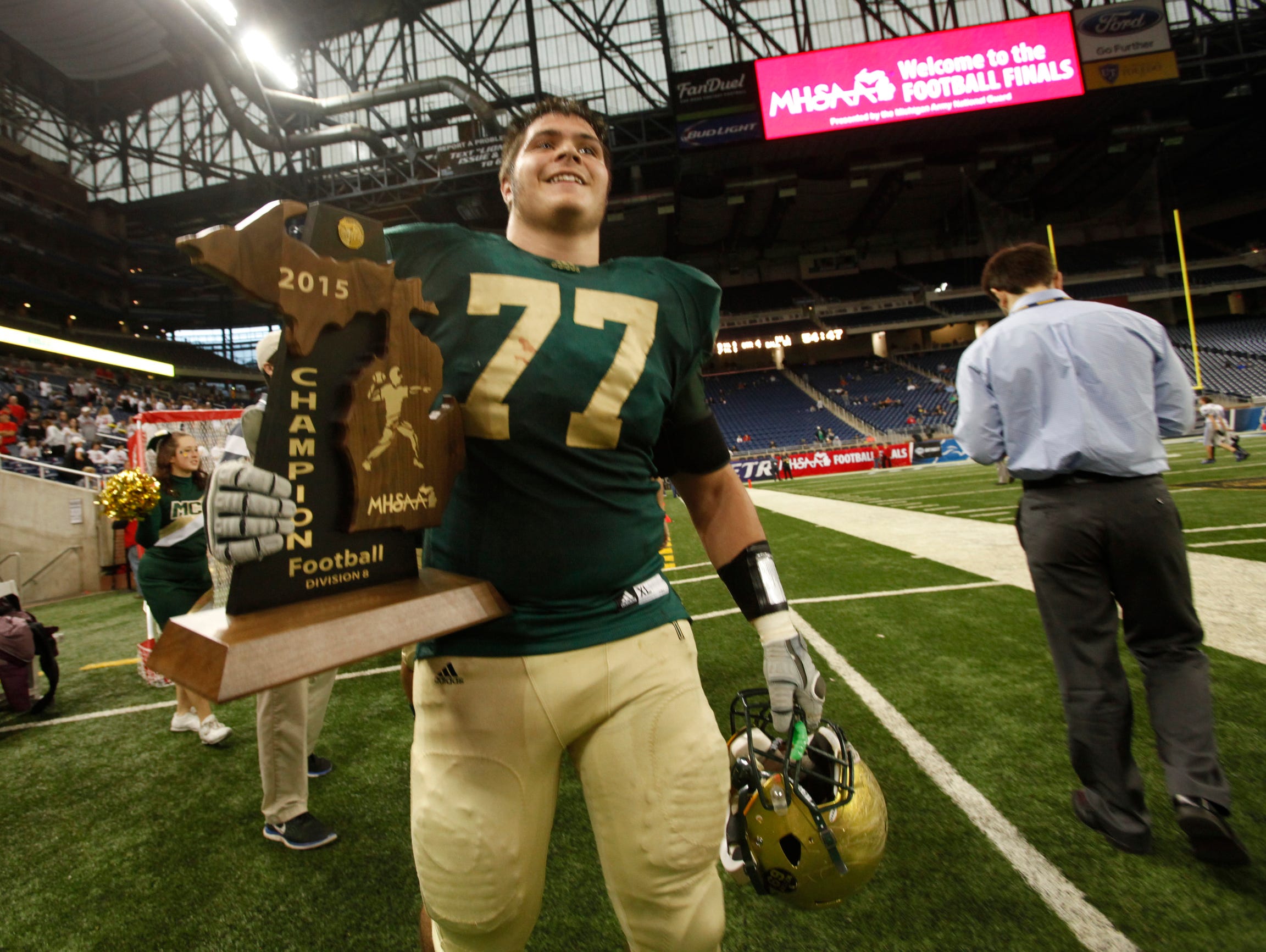 Muskegon Catholic Central 's Jacob Holt carries the trophy after a 7-0 victory over Waterford Our Lady of the Lakes in the MHSAA Division 8 state football championship at Ford Field in Detroit on Friday, Nov. 27, 2015.